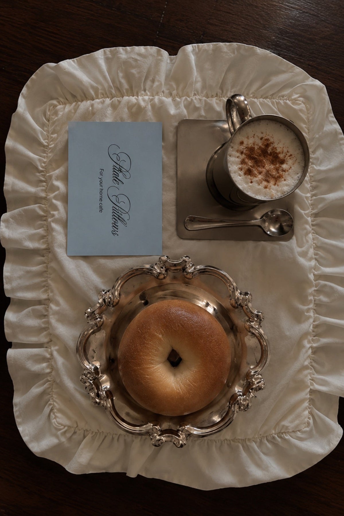 Silver bowl with bagel on a ruffled placemat, home cafe table